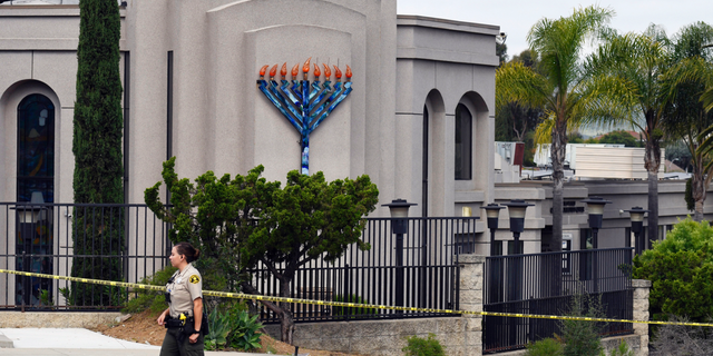 FILE - In this Sunday, April 28, 2019 file photo, a San Diego county sheriff's deputy stands in front of the Poway Chabad Synagogue in Poway, Calif. The gunman who attacked the synagogue last week fired his semi-automatic rifle at Passover worshippers after walking through the front entrance that synagogue leaders identified last year as needing improved security. The synagogue applied for a federal grant to better protect that area. The money, $150,000, was approved in September but only arrived in late March. "Obviously we did not have a chance to start using the funds yet," Rabbi Scimcha Backman told The Associated Press. (AP Photo/Denis Poroy, File)