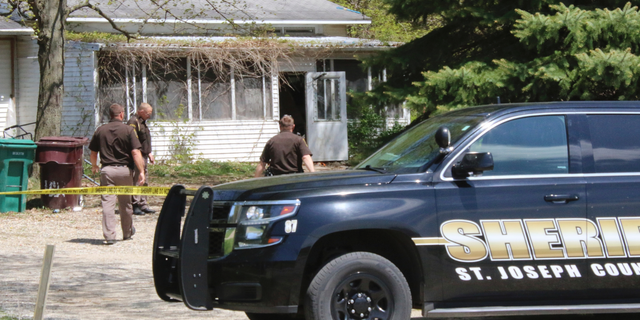 In this Monday, May 6, 2019 photo, St. Joseph County Sheriff deputies stand outside the site where a woman was fatally shot in Fawn River Township, Mich. Authorities say a 9-year-old is suspected in the shooting of a woman in her southern Michigan home. (Corky Emrick/Sturgis Journal via AP)