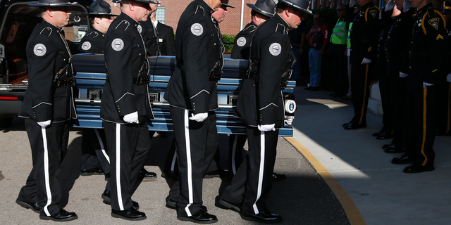 Members of the Biloxi Police Department Honor Guard escort the body of officer Robert McKeithen, into the First Baptist Church of Biloxi, Miss., Monday, May 13, 2019, for visitation. McKeithen was killed outside Biloxi's police station May 5. (AP Photo/Rogelio V. Solis)