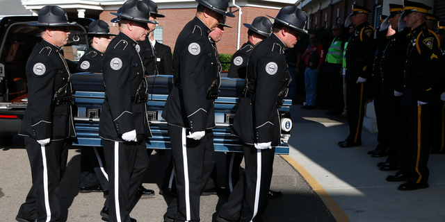 Members of the Biloxi Police Department Honor Guard escort the body of officer Robert McKeithen, into the First Baptist Church of Biloxi, Miss., Monday, May 13, 2019, for visitation. McKeithen was killed outside Biloxi's police station May 5. (AP Photo/Rogelio V. Solis)