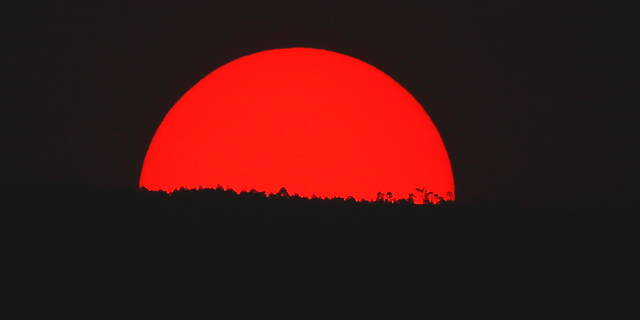 Tinted blood red by a thick cloud of smoke and pollution, the sun sets on the mountains above Mexico City, Monday, May 13, 2019. Mexico City's government has warned residents to remain indoors as forest and brush fires carpeted the metropolis in a smoky haze that has alarmed even many of those accustomed to living with air pollution. (AP Photo/Marco Ugarte)