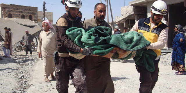 This photo provided by the Syrian Civil Defense group known as the White Helmets, shows members of the Syrian Civil Defense workers carrying a victim after a deadly airstrike hit a market killing several people in the village of Ras el-Ain, in the northwestern province of Idlib, Syria, Tuesday, May 7, 2019. Opposition activists say government forces have intensified their bombardment of rebel-held towns and villages in northwestern Syria. (Syrian Civil Defense White Helmets via AP)