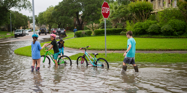 Children play in the Colony Bend neighborhood of Sugar Land, Texas, on Wednesday, May 8, 2019. Residents have been surprised that the water has not receded more quickly as it has in the past when the rain has stopped. More rain is forecast for the coming days. (Mark Mulligan/Houston Chronicle via AP)