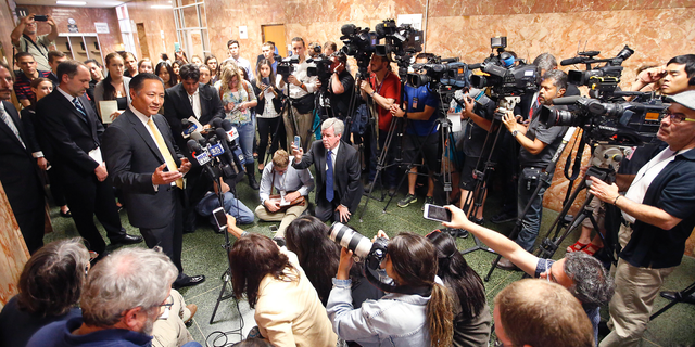FILE - In this July 7, 2015, file photo, San Francisco Public Defender Jeff Adachi, left, talks to members of the media after Francisco Sanchez' arraignment in San Francisco. A freelance journalist is vowing to protect his source after San Francisco police raided his home and office as part of a criminal investigation. Bryan Carmody tells the Los Angeles Times that officers handcuffed him Friday, May 10, 2019, as they confiscated items including his cell phone, computer and cameras. Authorities say the raid came during an ongoing probe into who leaked a confidential police report about the Feb. 22 death Adachi. (AP Photo/Tony Avelar, File)