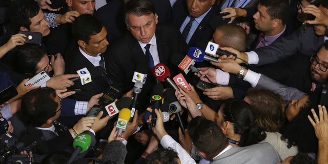 Brazil's President Jair Bolsonaro speaks to the press after signing a second decree that eases gun restrictions, at the Planalto presidential palace in Brasilia, Brazil, Tuesday, May 7, 2019. The decree opens Brazil’s market to guns and ammunition made outside of Brazil according to a summary of the decree. Gun owners can now buy between 1,000 -5,000 rounds of ammunition per year depending on their license, up from 50 rounds. Lower-ranking military members can now carry guns after 10 years of service. (AP Photo/Eraldo Peres)