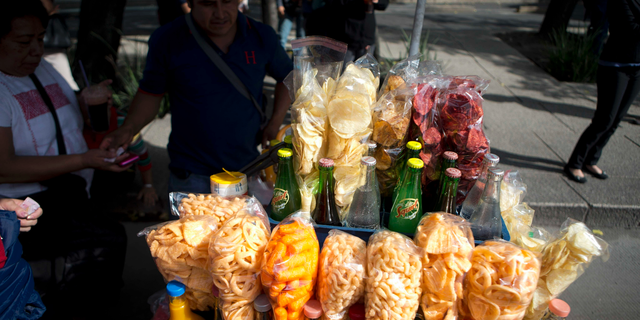 FILE - In this July 5, 2016 file photo, a street vendor sells fried snacks packaged in plastic bags in Mexico City. Mexico City lawmakers announced on Thursday, May 9, 2019 they have passed a ban on plastic bags, utensils and other disposable plastic items to take effect at the end of 2020, giving businesses more than a year to make the switch to biodegradable products. (AP Photo/Eduardo Verdugo, File)