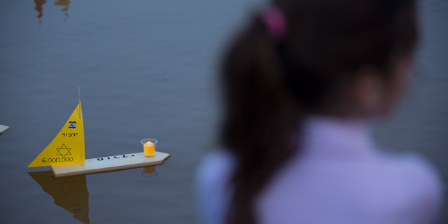 Handmade boats with the names of Nazi concentration camps float in a lake during ceremony marking the annual Holocaust Remembrance Day in Tel Aviv, Israel, Wednesday, May 1, 2019. Israel marking the annual Day of Remembrance for the six million Jewish victims of the Nazi genocide who perished during World War II. Hebrew reads "to remember". (AP Photo/Oded Balilty)