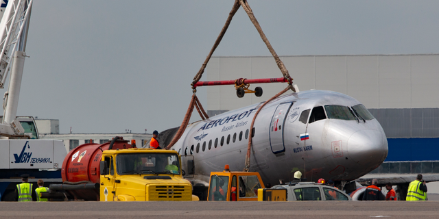 A crane lifts the damaged Sukhoi SSJ100 aircraft of Aeroflot Airlines in Sheremetyevo airport, outside Moscow, Russia, Monday, May 6, 2019. Russian emergency workers have recovered 41 bodies and two flight recorders from the wreckage of the plane that caught fire during an emergency landing in Moscow, officials said Monday as they sought to discover the cause of the disaster. (AP Photo)