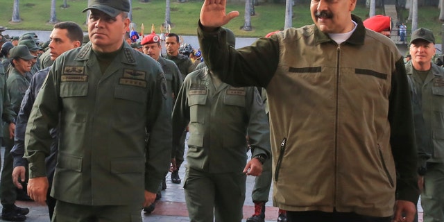 In this photo released by Miraflores Press Office, Venezuela's President Nicolas Maduro, right, accompanied by his Defense Minister Vladimir Padrino Lopez, waves upon his arrival to Fort Tiuna, in Caracas, Venezuela, Thursday, May 2, 2019. (Jhonn Zerpa/Miraflores Press Office via AP)