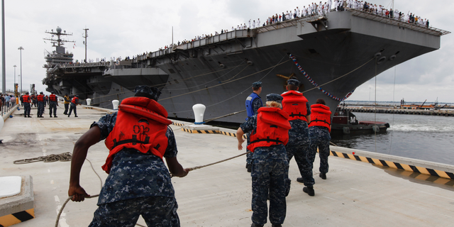 FILE - In this Aug. 7, 2012, file photo, Navy shore crew haul in lines as the nuclear powered aircraft carrier USS Abraham Lincoln arrives at Naval Station Norfolk in Norfolk, Va. The U.S. is dispatching the USS Abraham Lincoln and other military resources to the Middle East following “clear indications” that Iran and its proxy forces were preparing to possibly attack U.S. forces in the region, according to a defense official on May 5, 2019. (AP Photo/Steve Helber, File)