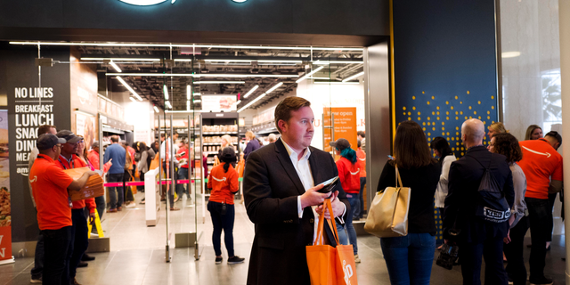 A customer carries his shopping bag as she walks out of a newly-opened Amazon Go store, Tuesday, May 7, 2019 in New York. The store will be the first Amazon Go store to accept cash. At its other shops, customers can only enter with an app that links to a credit card or an Amazon account.(AP Photo/Mark Lennihan)