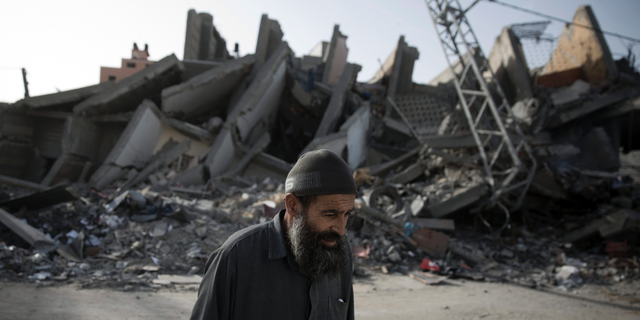An elderly Palestinian man walks next to the rubble of multi-story building was hit and destroyed on Sunday by Israeli airstrikes, in Gaza City, Monday, May. 6, 2019. The Israeli military has lifted protective restrictions on residents in southern Israel while Gaza's ruling Hamas militant group reported a cease-fire deal had been reached to end the deadliest fighting between the two sides since a 2014 war. (AP Photo/Khalil Hamra)