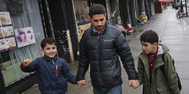In this March 21, 2019, photo, Sadek Ahmed walks with his sons Adel, 9, right, and Mutaz, 7, after picking them up from school in the Brooklyn borough of New York. Their mother, Amena Abdulkarem, is stuck in Yemen with her two younger sons, the boys’ brothers. Their family’s situation is representative of the toll that the Trump administration’s almost-forgotten travel ban has taken on an untold number of families. (AP Photo/Seth Wenig)