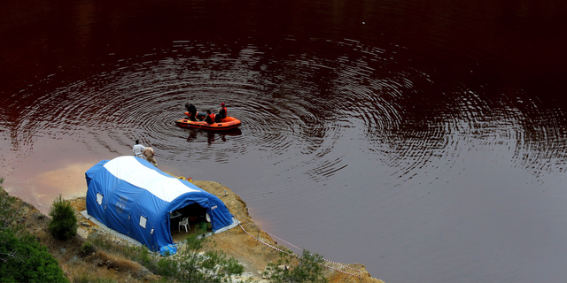 Members of the Cyprus Special Disaster Response Unit search for suitcases in a man-made lake, near the village of Mitsero outside of the capital Nicosia, Cyprus, Wednesday, May 1, 2019.