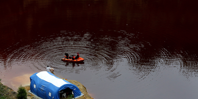 Members of the Cyprus Special Disaster Response Unit search for suitcases in a man-made lake, near the village of Mitsero outside of the capital Nicosia, Cyprus, Wednesday, May 1, 2019.