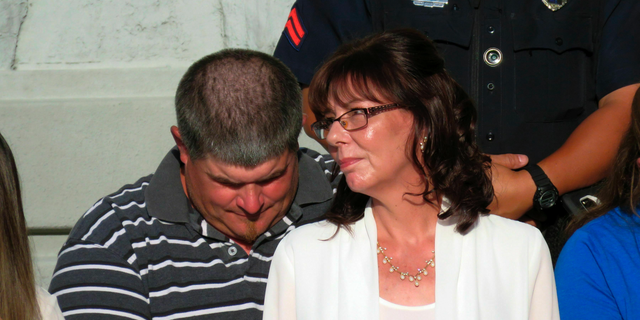 Pamela McKeithen, whose police officer husband was shot in the parking lot of the Biloxi Police Department on Sunday, listens to prayers during a memorial service for Patrolman Robert McKeithen in front of the department on Tuesday, May 7, 2019, in Biloxi, Miss. (AP Photo/Janet McConnaughey)