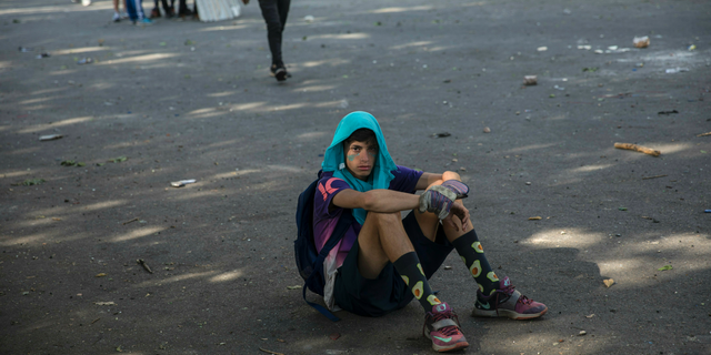 An anti-government protester rests during clashes with National Guard forces near La Carlota airbase in Caracas, Venezuela, Wednesday, May 1, 2019. Opposition leader Juan Guaido called for Venezuelans to fill streets around the country Wednesday to demand President Nicolas Maduro's ouster. Maduro is also calling for his supporters to rally. (AP Photo/Rodrigo Abd)