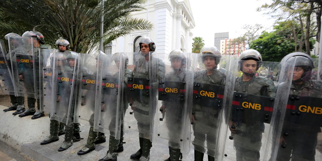 Venezuelan Bolivarian National guards officers form a cordon around the National Assembly building as the opposition-controlled congress met to discuss a move that could provide political cover for greater international involvement in the nation's crisis, in Caracas, Venezuela, Tuesday, May 7, 2019. Military police prevented journalists from entering the National Assembly, and some reporters were harassed by government supporters outside the building. (AP Photo/Fernando Llano)