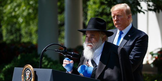 President Donald Trump looks on as Rabbi Yisroel Goldstein, survivor of the Poway, Calif synagogue shooting, speaks during a National Day of Prayer event in the Rose Garden of the White House, Thursday, May 2, 2019, in Washington. (AP Photo/Evan Vucci)