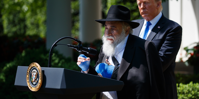 President Donald Trump looks on as Rabbi Yisroel Goldstein, survivor of the Poway, Calif synagogue shooting, speaks during a National Day of Prayer event in the Rose Garden of the White House, Thursday, May 2, 2019, in Washington. (AP Photo/Evan Vucci)