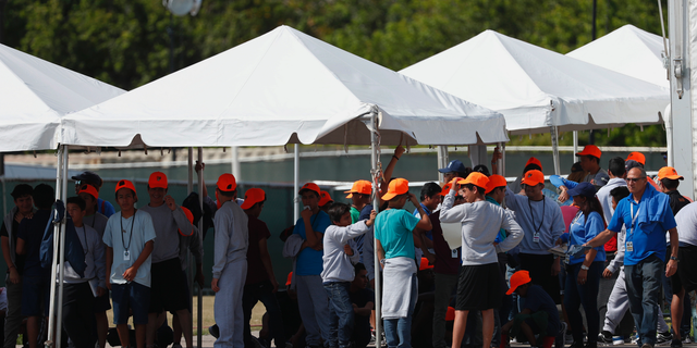 FILE - In this Monday, May 6, 2019 file photo, migrant children stand outside the Homestead Temporary Shelter for Unaccompanied Children in Homestead, Fla. The U.S. government is providing long-distance video counseling to teens housed at the country's largest migrant detention center as officials struggle to accommodate increasing numbers of minors illegally crossing the U.S.-Mexico border. Some mental health experts and human rights advocates say that may not be the best way to help young people coping with trauma. (AP Photo/Wilfredo Lee, File)