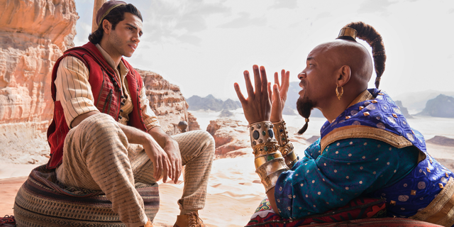 This image released by Disney shows Mena Massoud as Aladdin, left, and Will Smith as Genie in Disney's live-action adaptation of the 1992 animated classic "Aladdin."