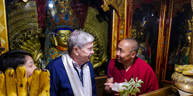 In this photo taken May 23, 2019, and released by the U.S. Embassy in Beijing, U.S. Ambassador to China Terry Branstad, left, speaks with a monk at the Jokhang Temple in Lhasa in western China's Tibet Autonomous Region. The U.S. ambassador to China urged Beijing to engage in substantive dialogue with exiled Tibetan Buddhist leader the Dalai Lama during a visit to the Himalayan region over the past week, the Embassy said Saturday. (U.S. Mission to China via AP)