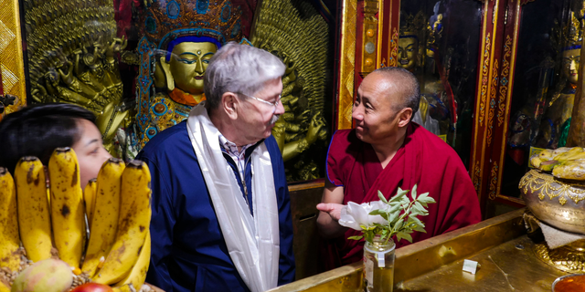 In this photo taken May 23, 2019, and released by the U.S. Embassy in Beijing, U.S. Ambassador to China Terry Branstad, left, speaks with a monk at the Jokhang Temple in Lhasa in western China's Tibet Autonomous Region. The U.S. ambassador to China urged Beijing to engage in substantive dialogue with exiled Tibetan Buddhist leader the Dalai Lama during a visit to the Himalayan region over the past week, the Embassy said Saturday. (U.S. Mission to China via AP)