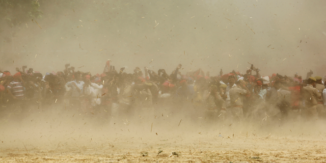 Supporters of Samajwadi Party president Akhilesh Yadav are seen through dust as a helicopter carrying Yadav lands at an election rally venue in Prayagraj, Uttar Pradesh, India, Sunday, May 5, 2019. With 900 million of India's 1.3 billion people registered to vote, the Indian national election is the world's largest democratic exercise. (AP Photo/Rajesh Kumar Singh)
