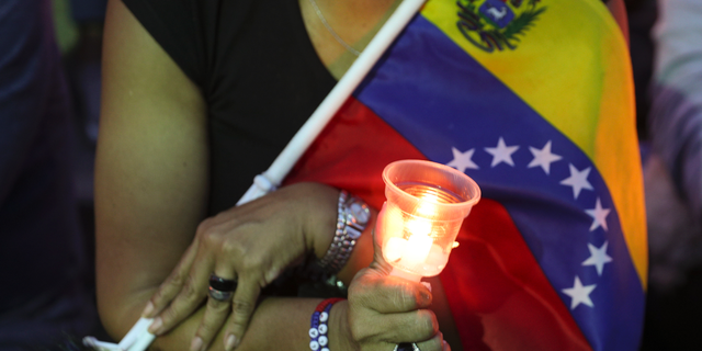 An opponent to Venezuela's President Nicolas Maduro holds a candle during a vigil for those killed in street fighting over the past week in Caracas, Venezuela, Sunday, May 5, 2019. Opposition leader Juan Guaid called in vain for a military uprising to overthrow President Nicolas Maduro, and five people were killed in clashes between protesters and police. (AP Photo/Martin Mejia)