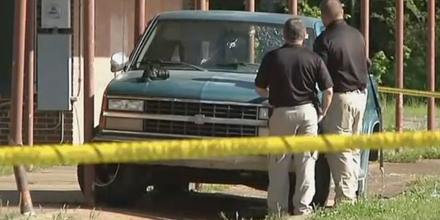 In this Friday, April 26, 2019 image made from video provided by KTEN, investigators inspect a pickup truck with bullet holes in its windshield in Hugo, Okla. Olivia Hill says Oklahoma police fired at William Devaughn Smith in the vehicle with her and her four children, with two of her kids suffering head wounds and another shot in the face. (KTEN via AP)