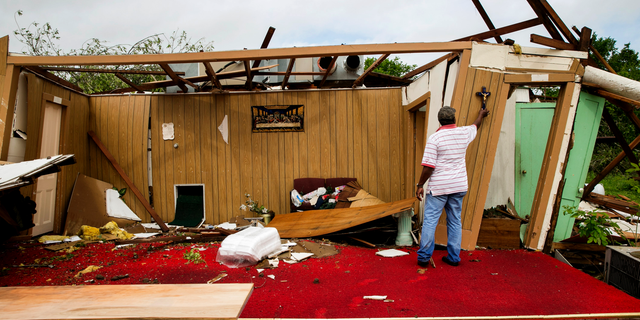 Melvin Jackson touches a cross that remained on the wall after a tornado destroyed Mt. Zion Baptist Church, a historic African American church, in La Grange, Texas, on Friday May 3, 2019. (Jay Janner/Austin American-Statesman via AP)