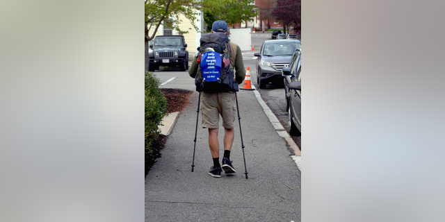 In this Wednesday, May 15, 2019 photo, U.S. Air Force veteran William Shuttlesworth walks up Market Street, in Newburyport, Mass., at the start of his planned cross-country hike to raise awareness for veterans' issues. Shuttleworth, 71, trained for several months carrying his full backpack while walking several miles each day. (Richard K. Lodge/The Daily News of Newburyport via AP)