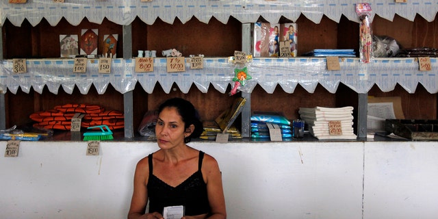 A worker holds a rationing booklet at a government-run food store called "Bodega" in Sagua La Grande, Villaclara Province, central Cuba November 8, 2009. REUTERS/Desmond Boylan (CUBA SOCIETY FOOD) 