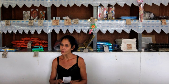 A worker holds a rationing booklet at a government-run food store called "Bodega" in Sagua La Grande, Villaclara Province, central Cuba November 8, 2009. REUTERS/Desmond Boylan (CUBA SOCIETY FOOD)