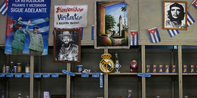 A poster showing late Cuban President Fidel Castro and his brother Raul, former president and now leader of the Communist Party, and the headline reading "The thriving and victorious revolution goes on" hangs inside a subsidized state store, or "bodega", where Cubans can buy basic products with a ration book they receive annually from the government, in Havana, Cuba April 10, 2019. The other photographs show late rebel heroes Camilo Cienfuegos (C) and Ernesto "Che" Guevara. REUTERS/Fernando Medina