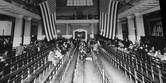 FILE - In this 1924 file photo, immigrants from Europe sit in the registry room at Ellis Island in New York harbor. Throughout history, the United States has used all sorts of physical or mental exams for immigrants seeking just to get into the country outside of becoming a citizen. (AP Photo/File)