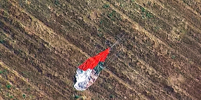 This photo taken from video provided by KABC-TV shows the parachute left by the pilot who ejected before his F-16 fighter jet crashed into a warehouse just outside March Air Reserve Base in Riverside, Calif., Thursday afternoon. (Associated Press)