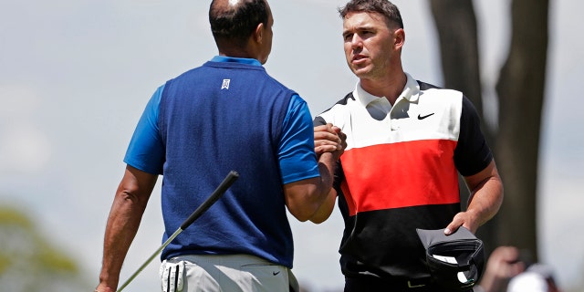Brooks Koepka, right, shakes hands with Tiger Woods after finishing the first round of the PGA Championship golf tournament, Thursday, May 16, 2019, at Bethpage Black in Farmingdale, N.Y. (AP Photo/Julio Cortez)