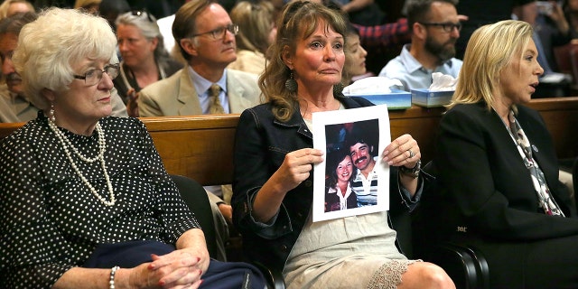 An attendee holds a photo of Cheri Domingo and her boyfriend Gregory Sanchez, who were killed in 1981, as she sits in the courtroom during the arraignment of Joseph James DeAngelo, the suspected "Golden State Killer" on April 27, 2018 in Sacramento, California. (Photo by Justin Sullivan/Getty Images)