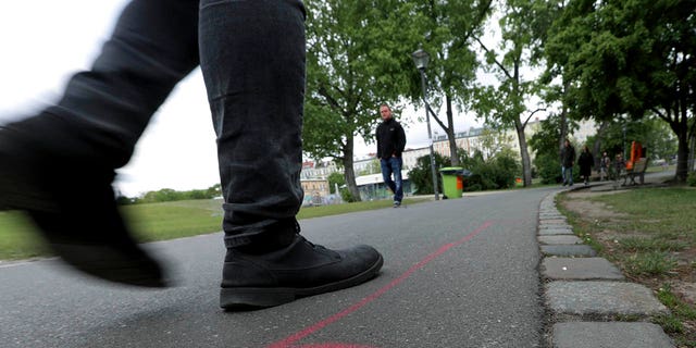 A man walks past a so called 'Drug Dealer Area' next to a traffic training course for kids at the public Goerlitzer Park in Berlin, Germany, Thursday, May 9, 2019. (AP Photo/Michael Sohn)