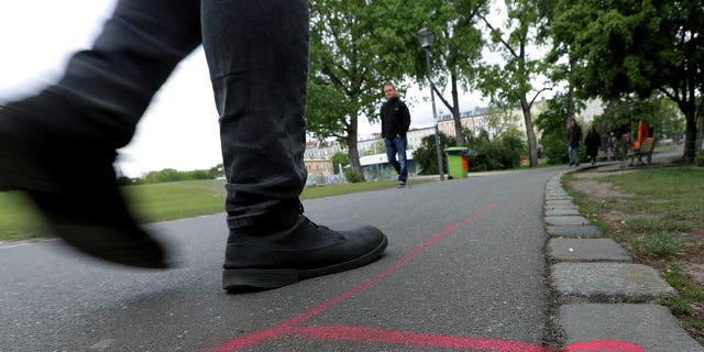 A man walks past a so called 'Drug Dealer Area' next to a traffic training course for kids at the public Goerlitzer Park in Berlin, Germany, Thursday, May 9, 2019. (AP Photo/Michael Sohn)