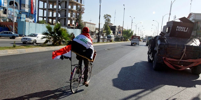 A man riding a bicycle with an Iraqi flag north of Kirkuk in October 2017. At least six explosions hit Kirkuk on Thursday, killing multiple people.