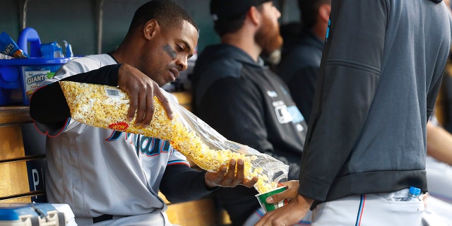 Miami Marlins' Curtis Granderson, left, shares popcorn with a teammate in the dugout during the third inning of the team's baseball game against the Detroit Tigers in Detroit, Tuesday, May 21, 2019. (AP Photo/Paul Sancya)