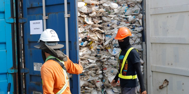 Workers open a container full of non-recyclable plastic detained by authorities at the west port in Klang, Malaysia, Tuesday, May 28, 2019. (AP Photo/Vincent Thian)