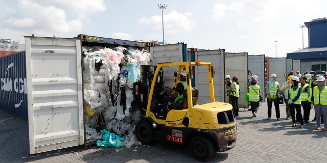 Officers from the Ministry of Environment examine a container full of non-recyclable plastic which was detained by authorities at the west port in Klang, Malaysia, Tuesday, May 28, 2019. (AP Photo/Vincent Thian)