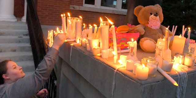 Julia Bodrero lights a candle on a monument following the vigil organized Monday by Elizabeth Shelley, 5 years old.