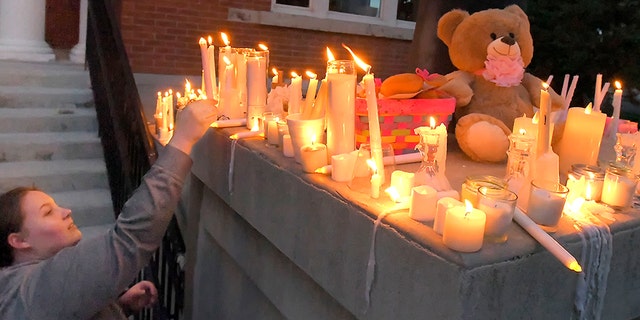 Julia Bodrero putting her candle onto a memorial following a vigil for 5-year-old Elizabeth Shelley on Monday.