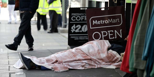 A man sleeps on the street in the central business district of Christchurch, New Zealand, Thursday, May 30, 2019.