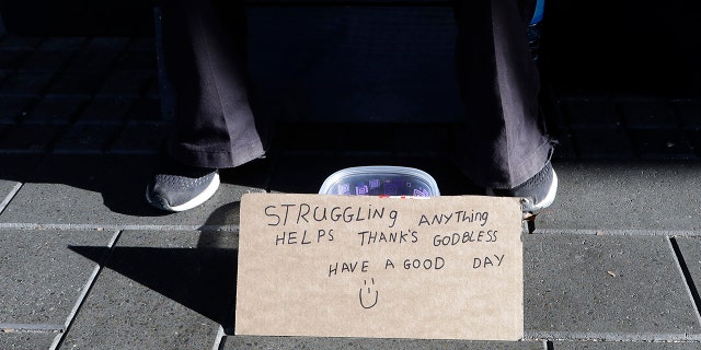 A man sits with a bowl asking for money in the central business district of Christchurch, New Zealand, Thursday, May 30, 2019.